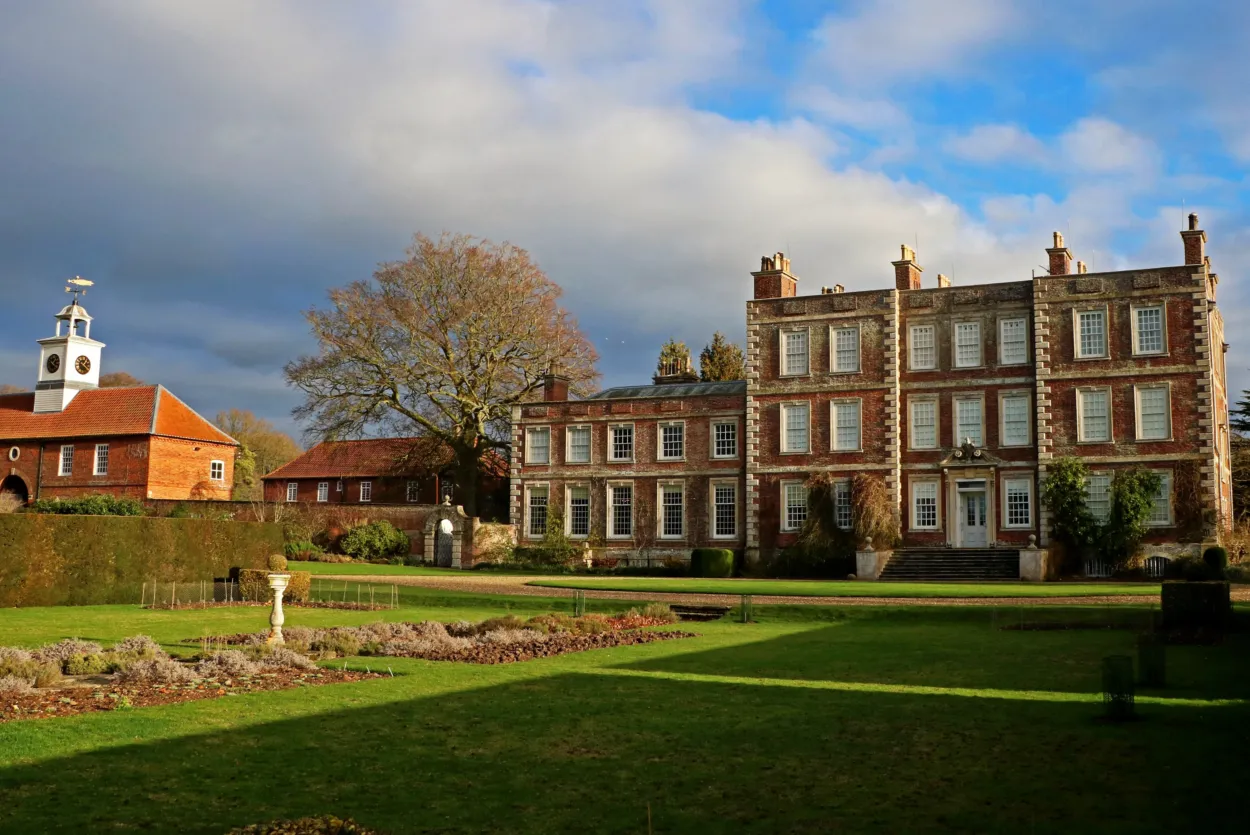 Gunby Hall bathed in warm autumn sunlight, surrounded by seasonal colours and mature trees, with the historic country house standing proudly at the heart of the estate.