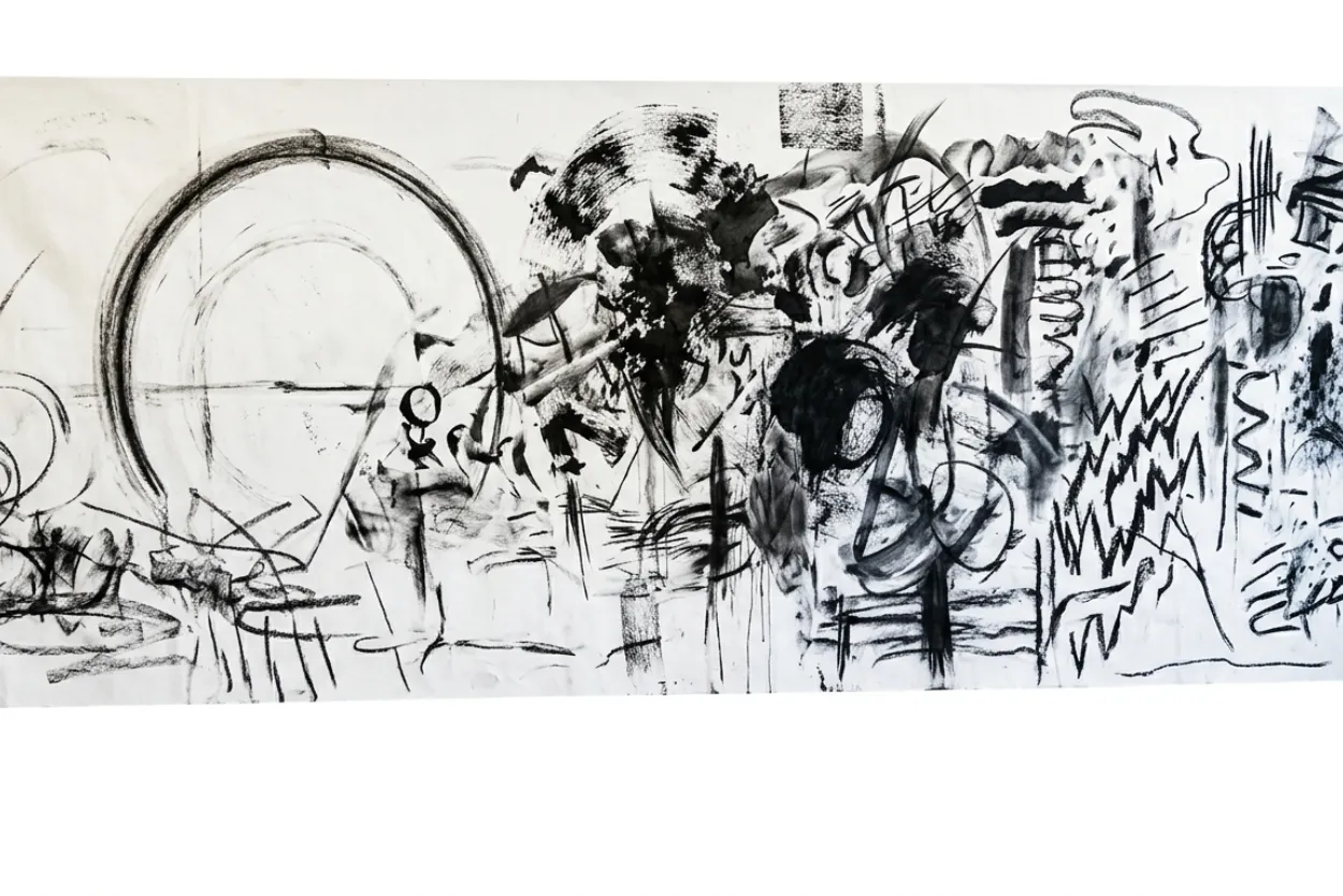 Abstract monochromatic mark-making and charcoal gestures across a long sheet of white paper.