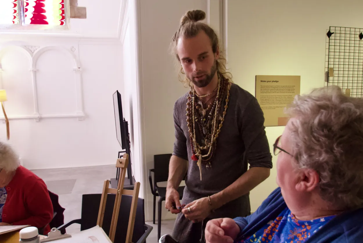 Artist Ralph Nel talks to two participants in a life drawing class