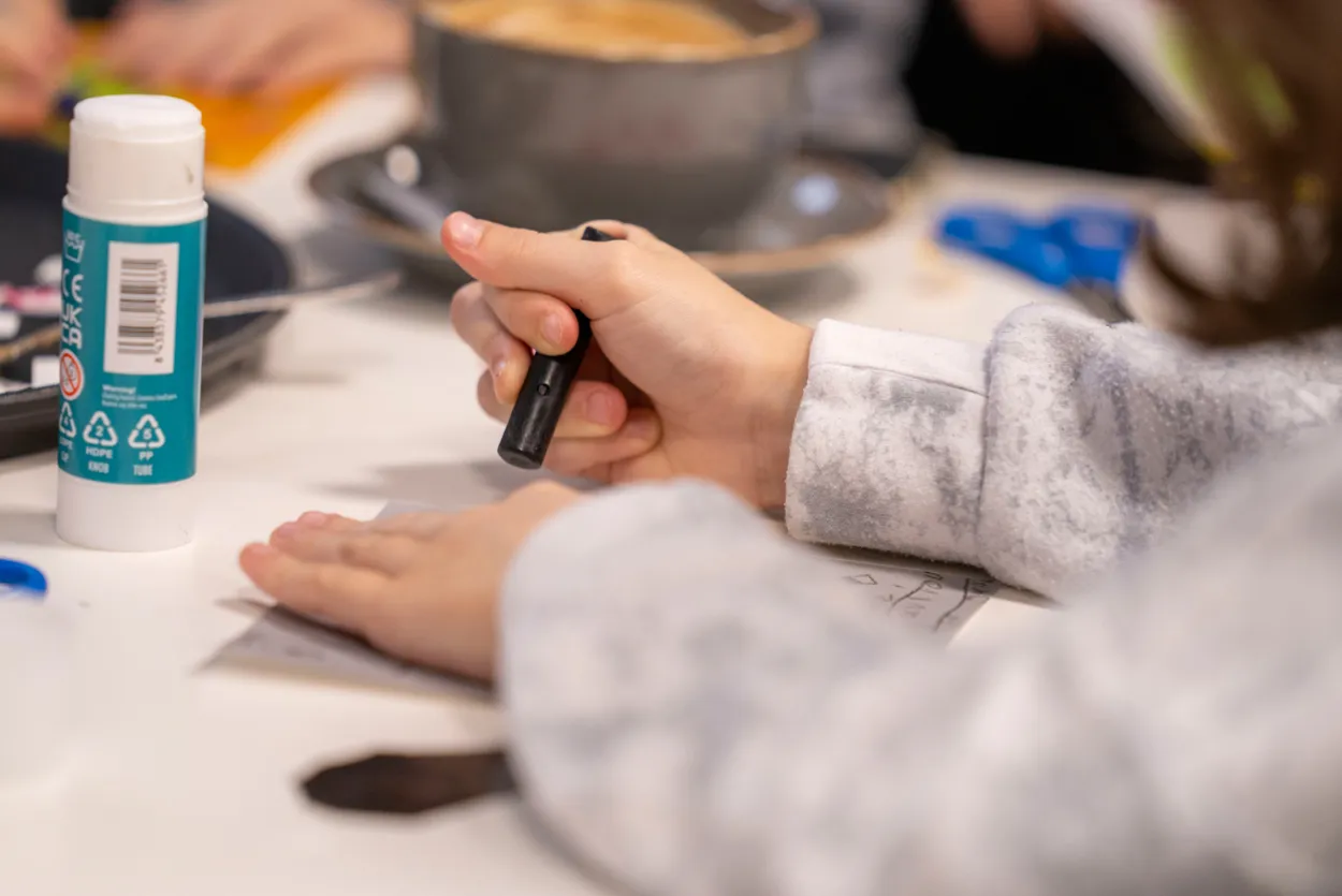 A close up of a young child holding a charcoal crayon