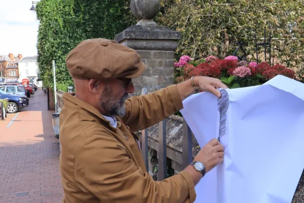 An artist drawing outside against a wall