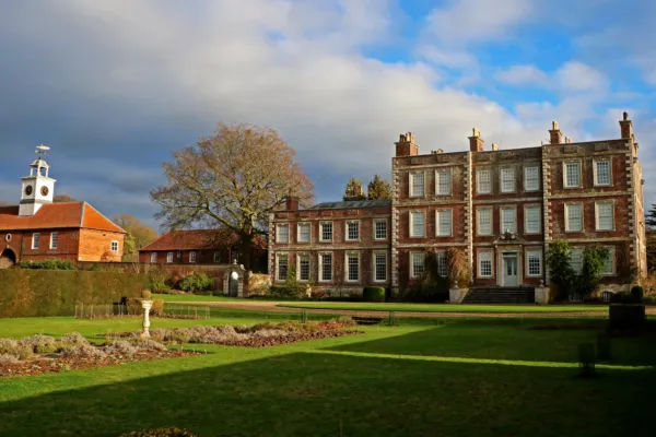 Gunby Hall bathed in warm autumn sunlight, surrounded by seasonal colours and mature trees, with the historic country house standing proudly at the heart of the estate.