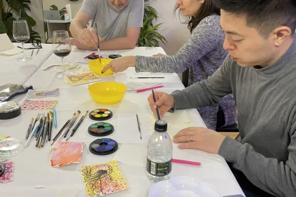 People creating in a group at a large table in a bright room