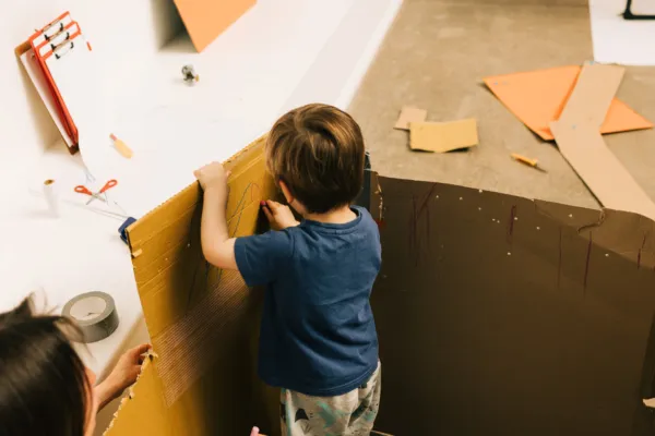 Young person exploring a large cardboard box with adult support