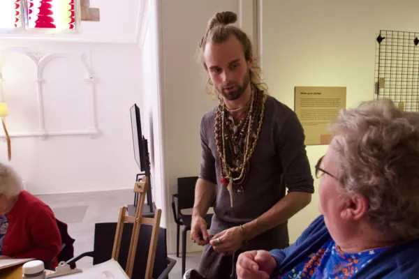 Artist Ralph Nel talks to two participants in a life drawing class